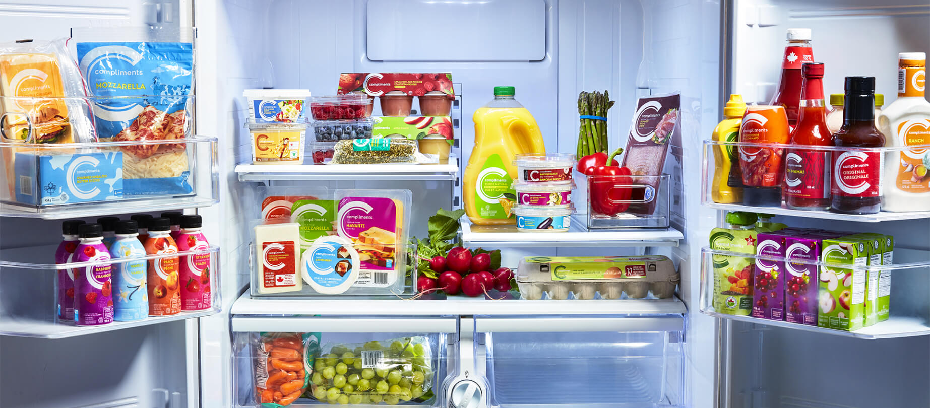 The inside of a fridge stocked with vegetables, eggs, cheeses, drinks and condiments