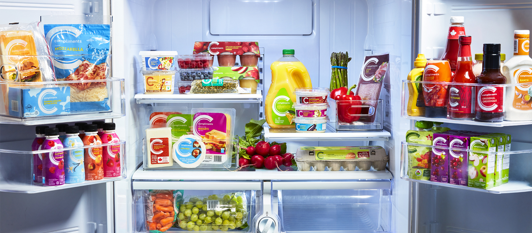 L’intérieur d’un réfrigérateur rempli de légumes, œufs, fromages, boissons et condiments