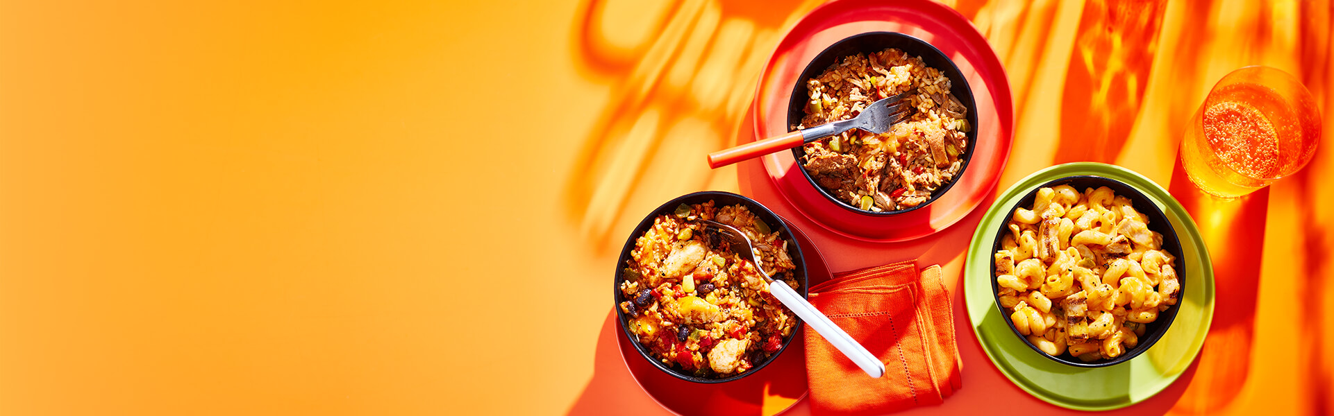 Mac n cheese and burrito bowls on an orange backdrop